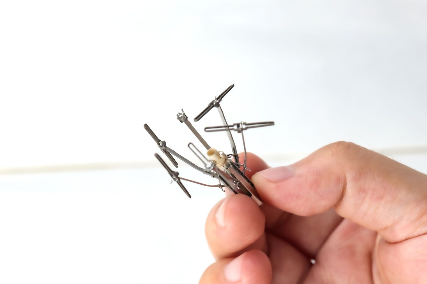 The miniature capsule in its deployed state, anchor arms open, held between two fingers