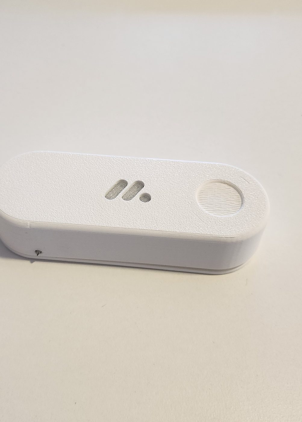 The finished product — a white desktop button with an embossed logo